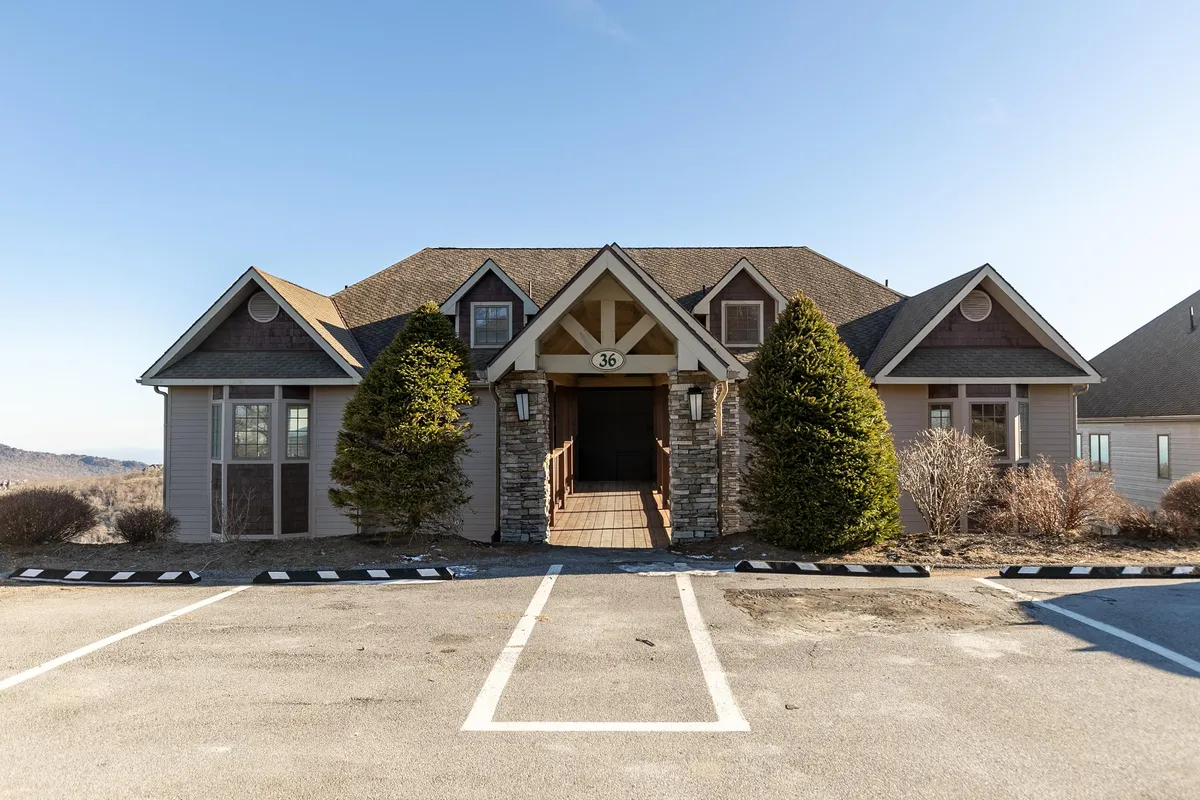 A welcoming view of the condo's front entrance framed by tasteful landscaping and stone details. The image captures the inviting pathway leading up to the door, with plenty of space outside for gatherings or relaxing after a day of adventure.